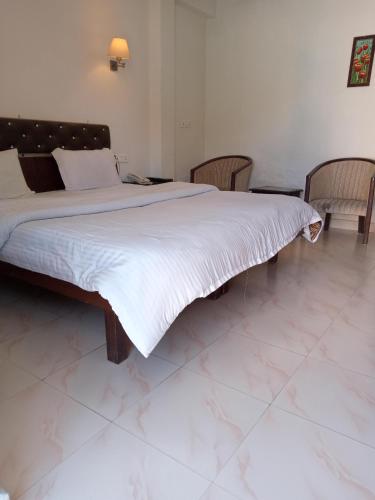 a large bed in a bedroom with two chairs at Dragon I Resorts in McLeod Ganj