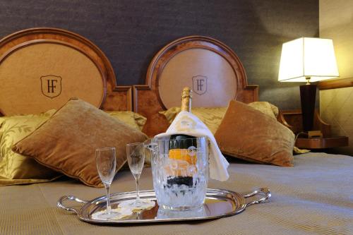 a tray with a bottle of wine and two glasses on a bed at Hotel Farnese in Rome