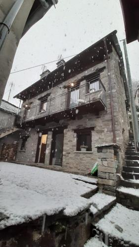 a building with snow on the ground in front of it at Locanda del Sasso Rooms in Crodo