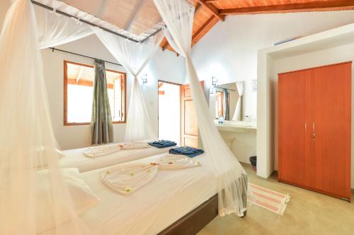 a bedroom with two beds with white mosquito nets at De Silva Palm Resort in Kalpitiya