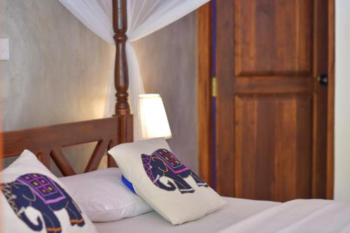 a bed with two pillows on top of it at De Silva Palm Resort in Kalpitiya