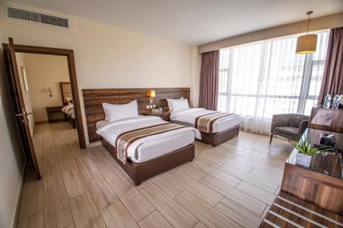 a hotel room with two beds and a mirror at Lacosta Hotel in Aqaba
