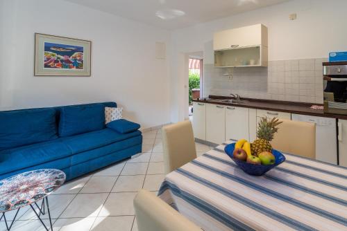 sala de estar con sofá azul y mesa con un bol de fruta en Apartments Irena Krk, en Krk