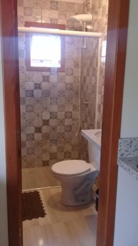 um banheiro com vaso sanitário, pia e janela em Pousada Moradas do Moçambique em Florianópolis