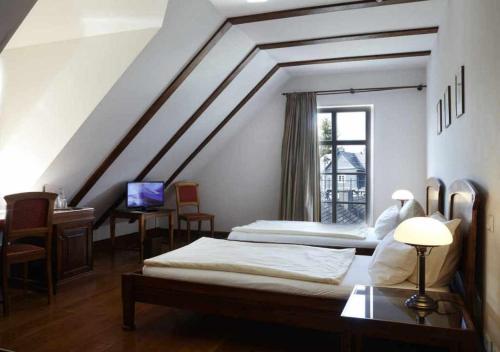 a bedroom with two beds and a desk and a window at Hotel Snorrenburg GmbH in Burbach