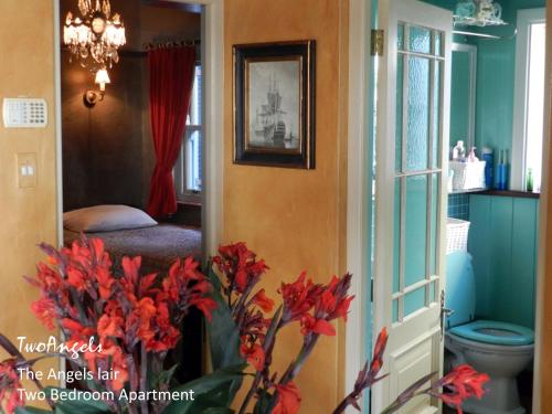 克尼斯納的住宿－兩個天使酒店，一间带卫生间的浴室和一个带红色鲜花的花瓶