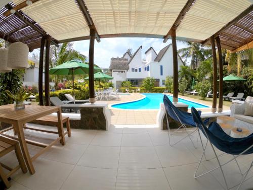 an outdoor patio with a table and chairs and a pool at Blue Bird in Pereybere