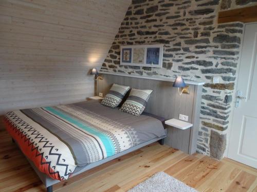 Bett in einem Zimmer mit einer Steinmauer in der Unterkunft Ty-Kanndi in Locmélar