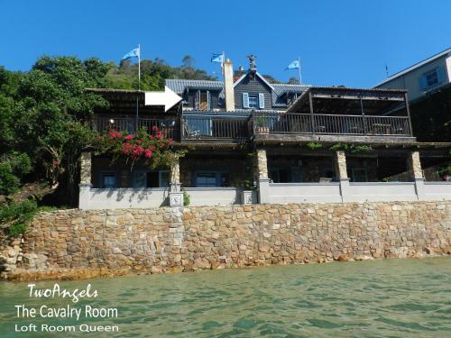a house on a stone wall next to the water at TwoAngels in Knysna