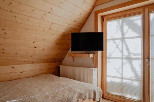 a bedroom with a flat screen tv in a wooden wall at Biolo i Corno Izba Mountain Chalets in Kościelisko
