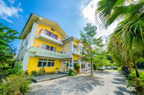 a yellow and white building with a palm tree at 光腳丫宜蘭民宿 in Dongshan