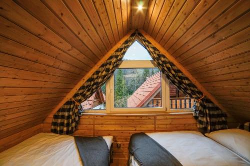 a bedroom in a log cabin with a window at Mała Osada domki z jacuzzi przy gondoli in Szczyrk