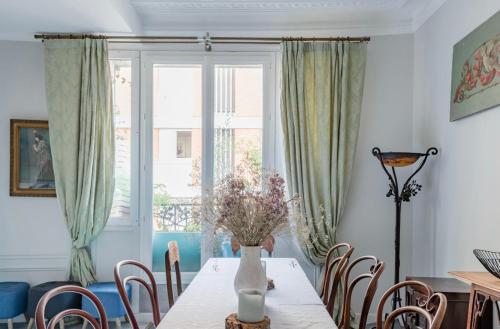 une salle à manger avec une table et un vase de fleurs. dans l'établissement Maison Chanzy, à Paris