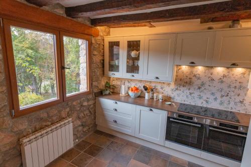 a kitchen with white cabinets and windows at La Borda del Feu in Guardia de Arés