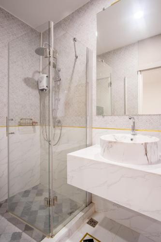 a white bathroom with a sink and a shower at Isara Boutique Hotel and Cafe in Phuket Town