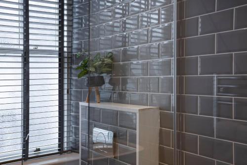 a room with gray tiled walls and a table with a plant at Fairmead in Ambleside