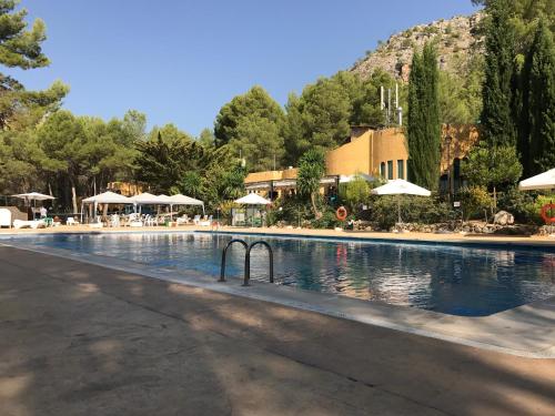 uma grande piscina com mesas e guarda-sóis em Camping La Puerta em Moratalla