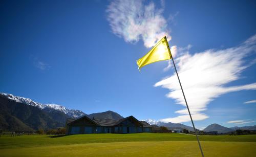 a yellow flag on a golf course with mountains in the background at Koura Bay Golf Resort in Kaikoura