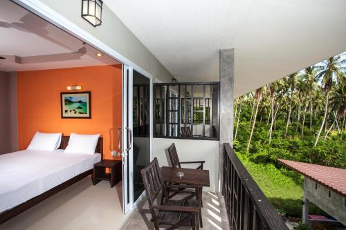 a bedroom with a bed and a balcony with a table at Baan Suan Ta Hotel in Ko Tao