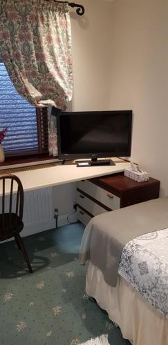 a bedroom with a desk with a flat screen tv at Milka's in Oxford