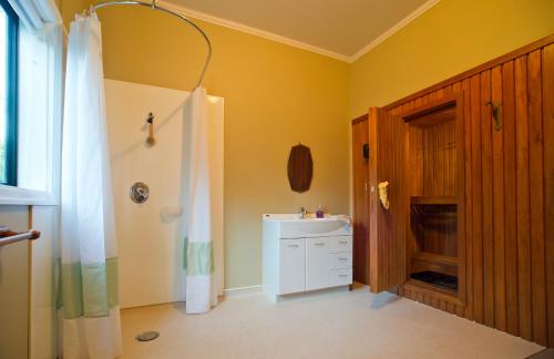 a bathroom with a white sink and a shower at Oak Lodge in Greymouth
