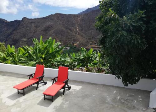twee rode stoelen op een balkon met uitzicht op de bergen bij Casa Lita in Hermigua