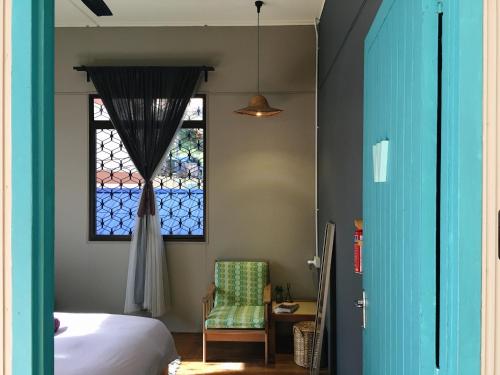 - une chambre avec une fenêtre, un lit et une chaise dans l'établissement Wogoxette Upstairs, A Private Kampung Stay In Cameron Highlands, à Cameron Highlands