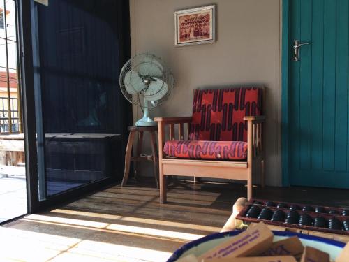 a living room with two chairs and a fan at Wogoxette Upstairs, A Private Kampung Stay In Cameron Highlands in Cameron Highlands
