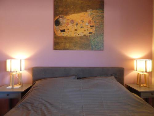 een slaapkamer met een bed met 2 lampen en een schilderij bij Le Sud sur Plage in Mèze