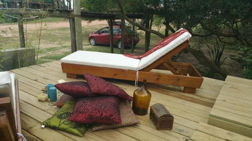 a chair on a deck with pillows on a table at Las Casquivanas in Punta Del Diablo