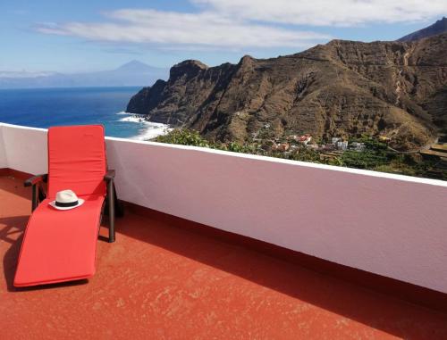 een rode stoel op een balkon met uitzicht op de oceaan bij Casa Lita in Hermigua