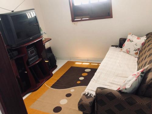 a living room with a couch and a flat screen tv at Casa Verde na Chapada Diamantina in Palmeiras