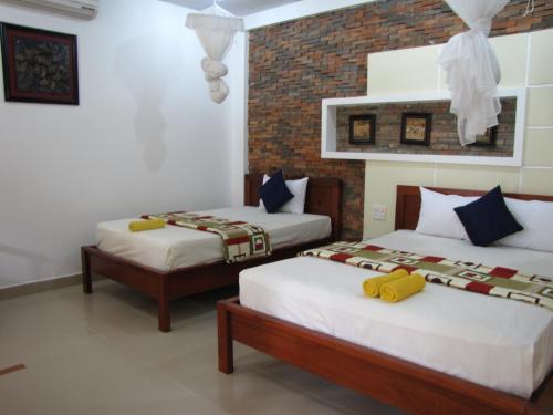 a bedroom with two beds and a brick wall at Nhat Quang Bungalow in Mui Ne