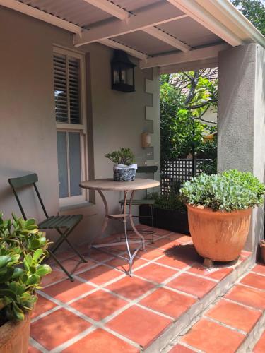 a patio with a table and two potted plants at Elton in Cape Town