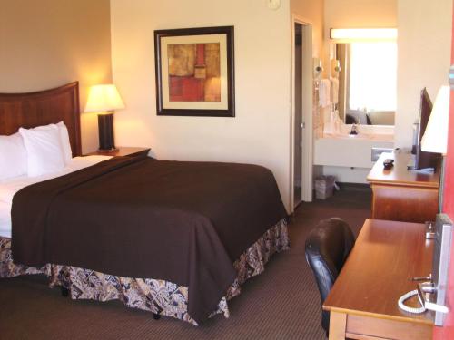 a hotel room with a bed and a bathroom at Trade Winds Central Inn in Tulsa