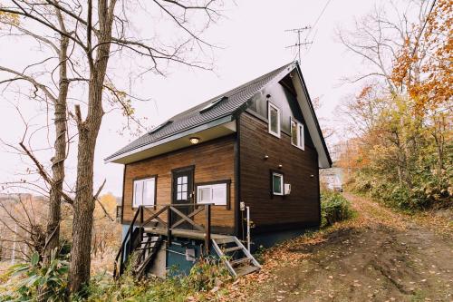 a house with a black roof on a hill at LAKE TOYA Great view log cabin in Lake Toya