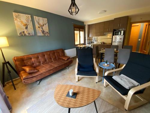 una sala de estar con un sofá de cuero marrón y sillas en Apartamento Turístico Javalambre Snow, en Camarena de la Sierra