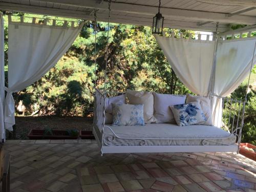 a white couch sitting on a patio with curtains at Egesta, villa with private pool in Calatafimi