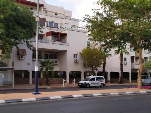 een witte auto geparkeerd voor een gebouw bij Nelly's Housing Unit in Eilat