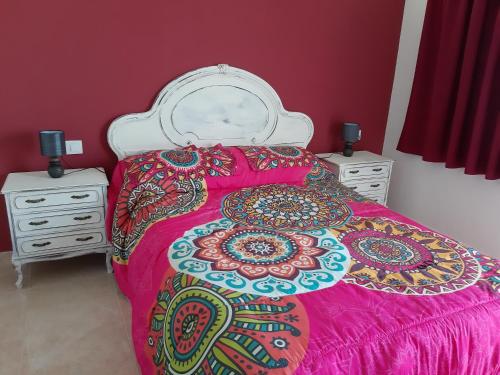 uma cama com uma colcha rosa e duas mesas de cabeceira em Casa Altavista em Vilaflor