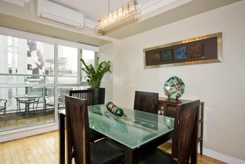 a dining room with a glass table and chairs at Yonge Suites Apart Hotel in Toronto