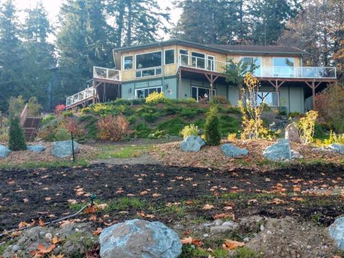 a house on a hill with rocks in front of it at Sunrise Suite on the Sound in Anacortes