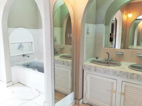 a bathroom with three sinks and a tub and two mirrors at Rockview Guest House in Port Edward