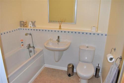 a bathroom with a white toilet and a sink at Airdrie Apartments in Airdrie