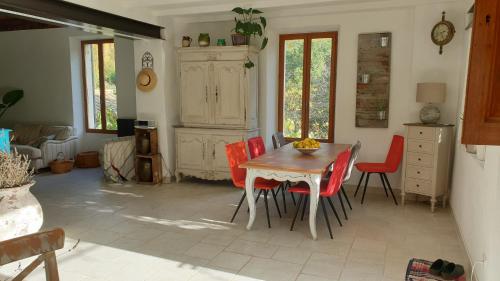 a dining room with a table and red chairs at Le Ptit Cottage in Nyons