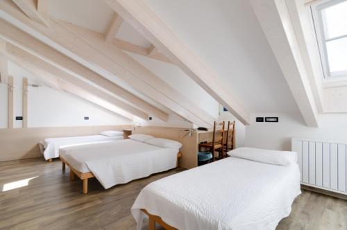 a attic bedroom with two beds and a window at Affittacamere La Ferrata in San Michele allʼAdige