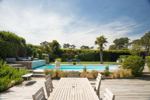 a backyard with a wooden table and a swimming pool at Chambre d'Hôtes Etchebri in Anglet