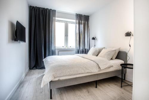 ein weißes Schlafzimmer mit einem Bett und einem Fenster in der Unterkunft Apartament Nadbystrzycka no. 02 in Lublin