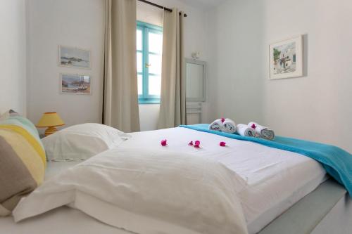a white bed with some pink roses on it at Ragousis Apartments in Parikia