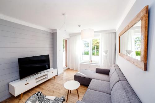 salon z kanapą i telewizorem w obiekcie FARO Apartamenty Polanki Park z basenami w Kołobrzegu